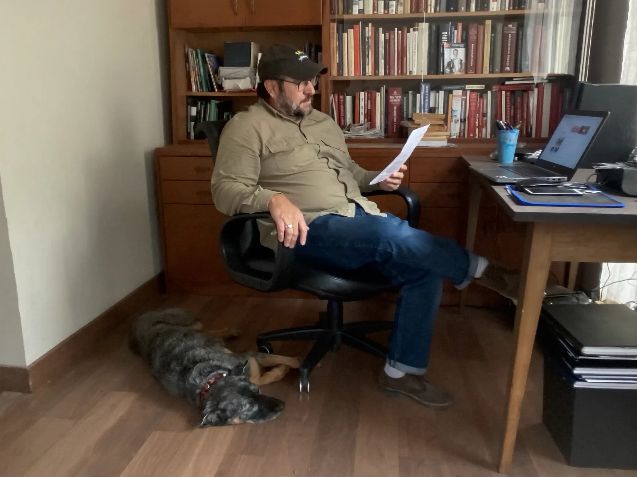 Mann liest entspannt am Laptop, Hund schläft daneben
